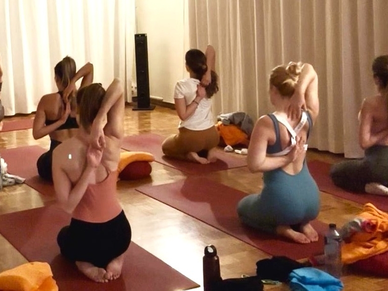 Grupo practicando ejercicio de movimiento consciente tipo yoga en sala sobre esterillas