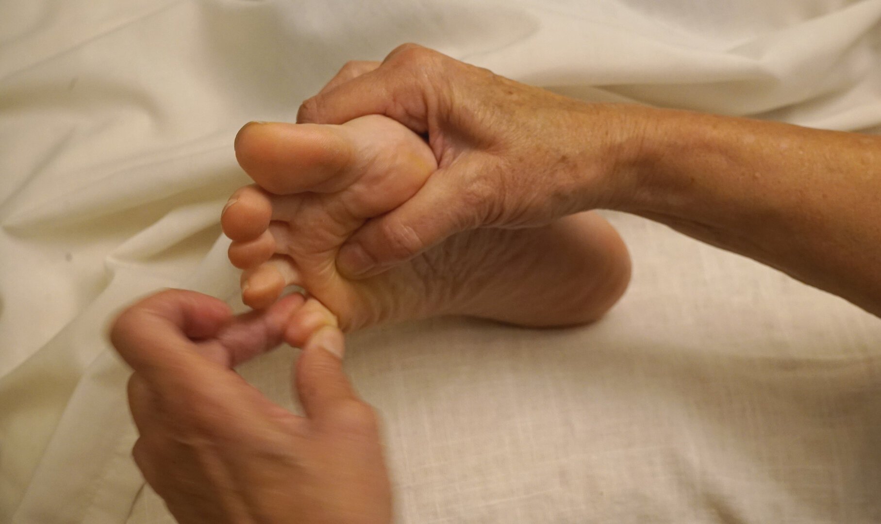 Sesión de reflexología podal con masaje en los dedos del pie sobre camilla